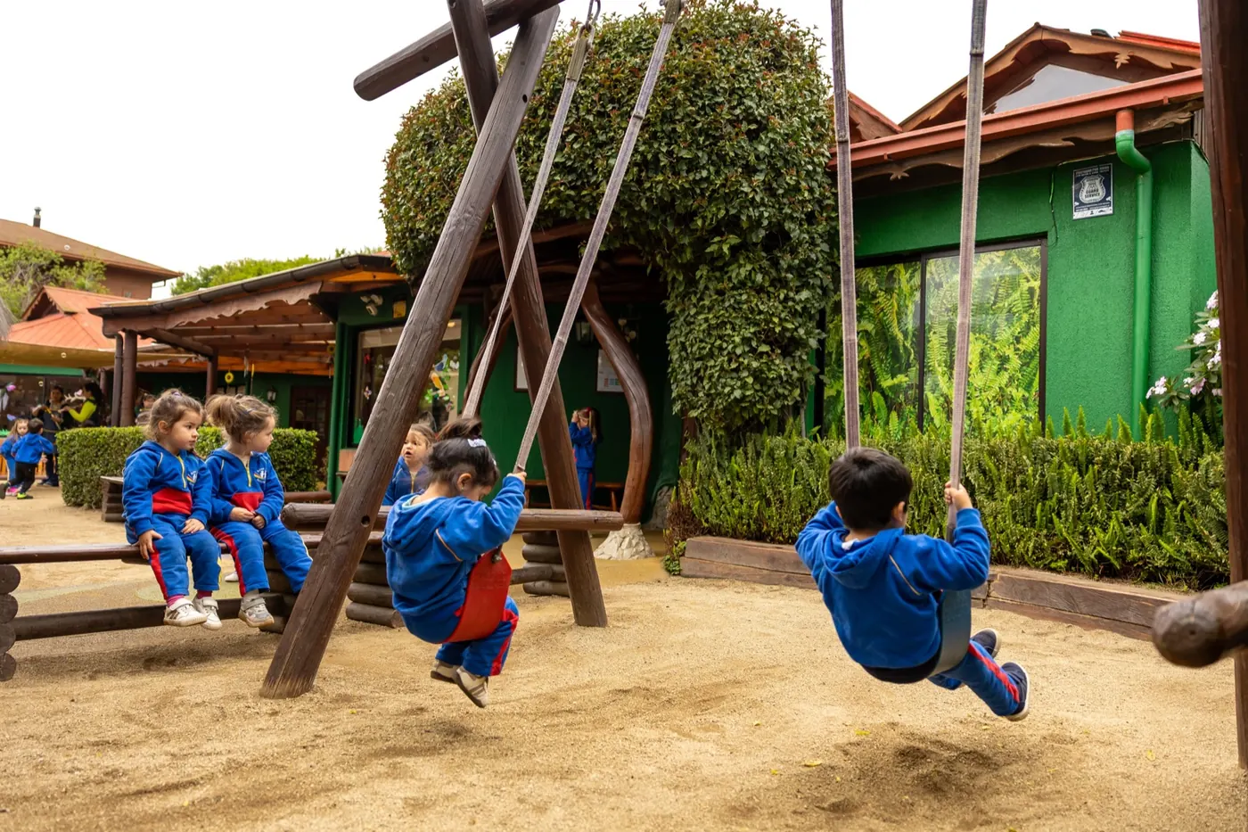 Niños en los columpios de madera del patio del Jardín Infantil Arco Iris en Concón