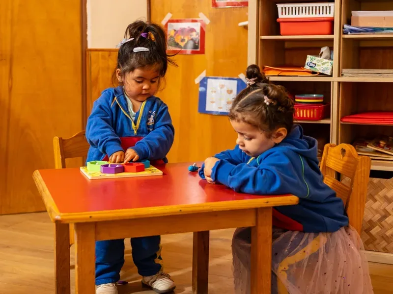 Niñas trabajando con material Montessori de madera en la mesa, Jardín Infantil Arco Iris en Concón